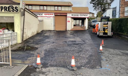 Old tarmacadam car park in Glasgow coned off ready for tarmac repair
