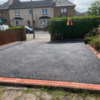 Super smooth tarmacadam yard in Scotland, laid by Scottish & North East England surfacing contractor Armstrong's Roads & Driveways Smooth tarmac apron with red brick edge, Scotland